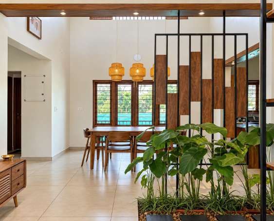Dining area seen through a steel-and-teak partition with plants