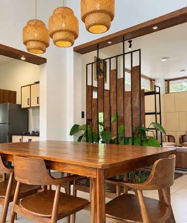 Dining table under rattan pendants beside a timber slat partition