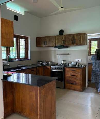 Open kitchen with teak cabinets and a black granite island